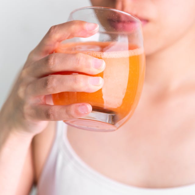 5 lợi ích khi uống nước ép cà rốt mỗi ngày- Ảnh 1. Người phụ nữ ăn chay đang uống nước ép rau củ giải độc từ cà rốt tươi. Người phụ nữ đang cầm ly nước ép cà rốt tươi.
